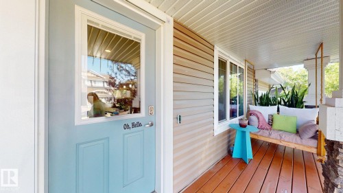 Covered front porch featuring wood-finish flooring, a light blue door with an inset window, and horizontal siding - 6824 Evans Wynd Nw, Edmonton, AB - Outdoor With Deck Patio Veranda With Exterior