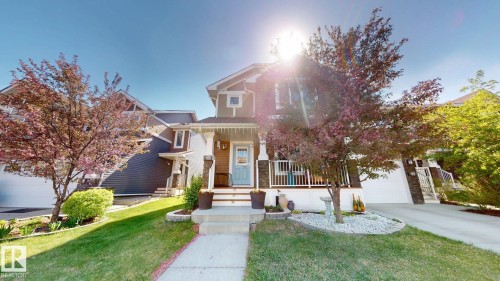 Contemporary home featuring a welcoming front porch with white railings and columns with stone accents - 6824 Evans Wynd Nw, Edmonton, AB - Outdoor With Facade