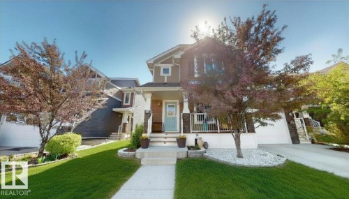 Two-story residence featuring a covered front porch with white railings and stone-wrapped columns - 6824 Evans Wynd Nw, Edmonton, AB 