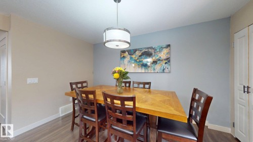 Dedicated dining area featuring wood-finish flooring and a contemporary drum pendant light fixture - 6824 Evans Wynd Nw, Edmonton, AB - Indoor Photo Showing Dining Room