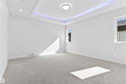 Spacious room featuring light gray carpet flooring, a tray ceiling with accent lighting, and recessed lighting - 