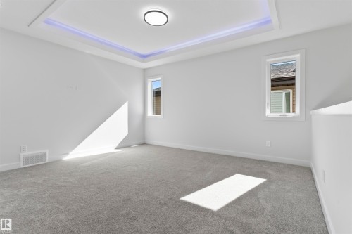 Recessed ceiling with perimeter lighting, a central flush-mount fixture, two windows, wall-to-wall carpeting, and white baseboards - 208 Falcon Crescent, Leduc, AB - Indoor Photo Showing Other Room