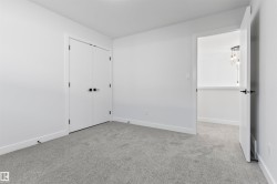Spacious room featuring light gray carpeting, white walls, and bright white baseboards - 