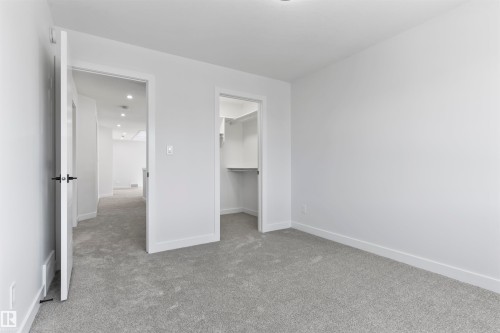 Carpeted room featuring a white door with black hardware, white walls, and a walk-in closet with shelving - 208 Falcon Crescent, Leduc, AB - Indoor Photo Showing Other Room