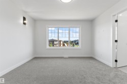 Bright interior room featuring a large window with grilles, neutral gray carpeting, white baseboards, and a contemporary wall sconce - 
