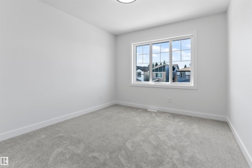 Bright room featuring a large window with multiple panes, light gray carpeting, crisp white walls, and a recessed ceiling light - 208 Falcon Crescent, Leduc, AB - Indoor Photo Showing Other Room
