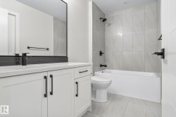 Contemporary bathroom featuring a white vanity with integrated sink, a large wall-mounted mirror, and a sleek matte black faucet - 