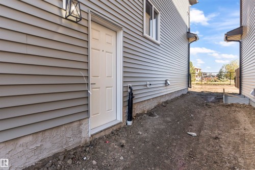 Exterior featuring horizontal siding, a paneled entry door, a window with white trim, and an exterior wall lantern - 208 Falcon Crescent, Leduc, AB - Outdoor With Exterior