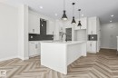 Kitchen featuring a white island, white cabinetry, dark subway tile backsplash, recessed lighting, and wood-finish herringbone flooring - 208 Falcon Crescent, Leduc, AB  - Indoor Photo Showing Kitchen With Upgraded Kitchen 