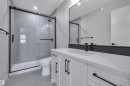 Contemporary bathroom featuring a spacious white vanity with ample storage, a light-toned countertop, and modern black hardware - 208 Falcon Crescent, Leduc, AB  - Indoor Photo Showing Bathroom 