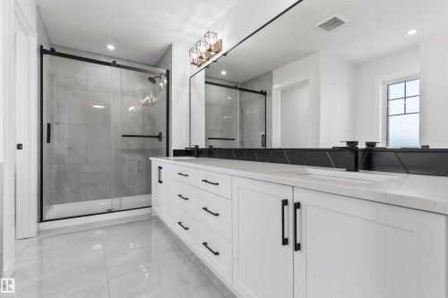 Bathroom featuring a dual vanity with white cabinetry, black hardware, and integrated sinks - 208 Falcon Crescent, Leduc, AB - Indoor Photo Showing Bathroom
