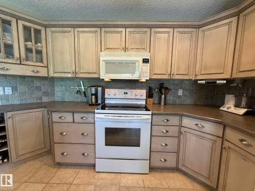 Kitchen featuring extensive cabinetry with decorative molding and glass-front upper cabinets - 5604 57 Avenue, Beaumont, AB 