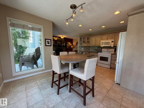 Kitchen featuring a central dining island, stainless steel appliances, neutral cabinetry, a tile backsplash, and recessed lighting - 5604 57 Avenue, Beaumont, AB 