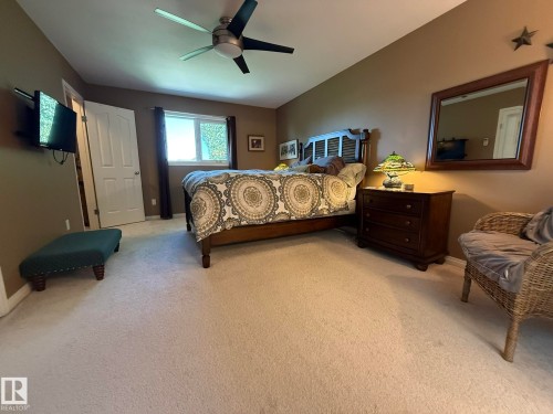 Photo of the Primary Bedroom with carpet, a ceiling fan, a window, and a white paneled door - 5604 57 Avenue, Beaumont, AB 