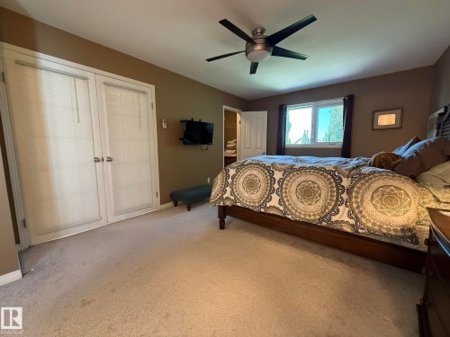 Carpeted interior space featuring a ceiling fan with integrated lighting, a window with exterior views, and double French doors with interior blinds - 5604 57 Avenue, Beaumont, AB 