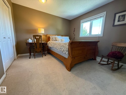 Carpeted room featuring a double-pane window with white trim, neutral wall color, and a built-in bi-fold closet - 5604 57 Avenue, Beaumont, AB 