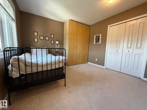 Carpeted room featuring a built-in wardrobe, a window with blinds, and bi-fold closet doors - 5604 57 Avenue, Beaumont, AB 