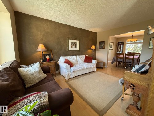 Living space featuring light wood-finish flooring and a textured accent wall - 5604 57 Avenue, Beaumont, AB 