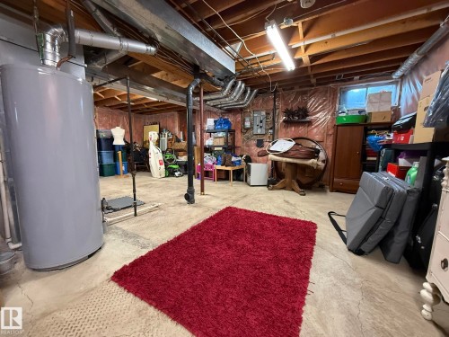 Utility room featuring a water heater, exposed ductwork, and concrete flooring - 5604 57 Avenue, Beaumont, AB 