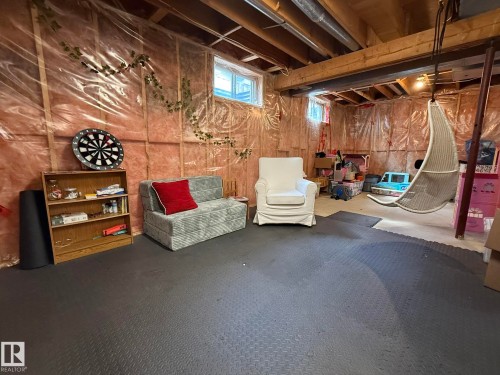 Unfinished basement featuring exposed wood beams, visible insulation, and multiple windows - 5604 57 Avenue, Beaumont, AB 