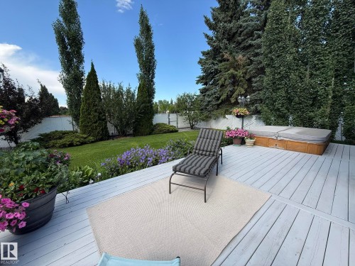 Spacious backyard featuring a light-painted wood deck, built-in hot tub, and a manicured lawn - 5604 57 Avenue, Beaumont, AB 