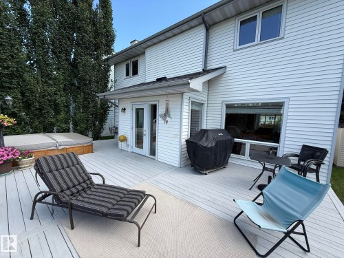 Expansive multi-level wood deck with a built-in hot tub, offering direct access to the interior via a white French door - 5604 57 Avenue, Beaumont, AB 