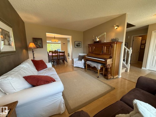 Living area featuring light wood-finish flooring, neutral-toned walls, and a recessed dining area with a chandelier - 5604 57 Avenue, Beaumont, AB 
