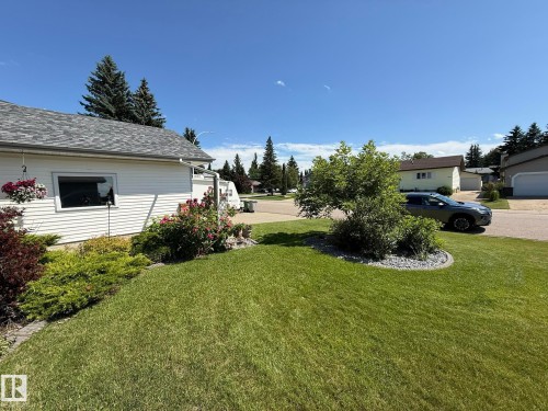 Expansive front lawn featuring mature landscaping, decorative rock borders, and established shrubs - 5604 57 Avenue, Beaumont, AB 