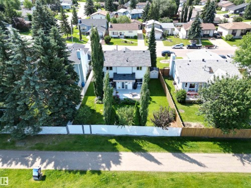 Rear exterior featuring an upper-level deck, lower-level patio, and a fenced yard with mature landscaping - 5604 57 Avenue, Beaumont, AB 