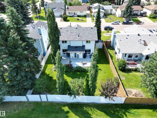 Rear exterior of the property featuring a light-colored siding, a dark shingle roof, and a concrete patio - 5604 57 Avenue, Beaumont, AB 