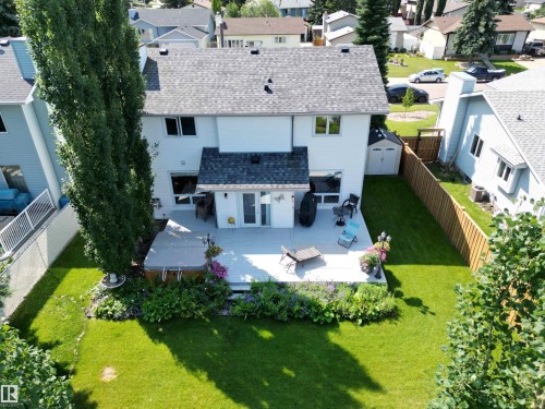 Expansive backyard featuring a large elevated deck, manicured lawn, established garden beds, and mature trees - 5604 57 Avenue, Beaumont, AB 