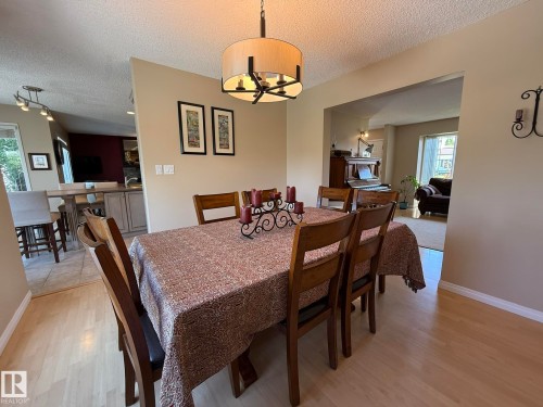 Dining area featuring wood-finish flooring, a contemporary drum pendant light fixture, and an open entryway to an additional living space - 5604 57 Avenue, Beaumont, AB 
