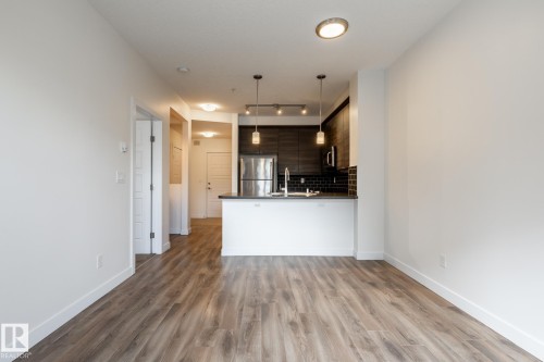 Open-concept living space featuring wood-finish flooring - #215 2590 Anderson Wy Sw, Edmonton, AB - Indoor Photo Showing Kitchen
