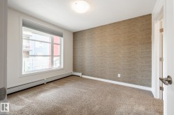Neutral-toned wall covering, broad window, baseboard heating, recessed ceiling fixture, and textured carpeting - 