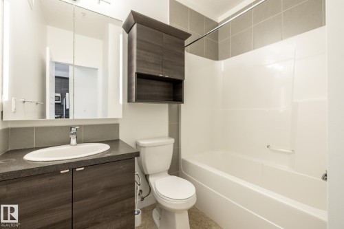 Contemporary bathroom featuring a dark wood-finish vanity with an integrated oval sink and dark countertop - #215 2590 Anderson Wy Sw, Edmonton, AB - Indoor Photo Showing Bathroom