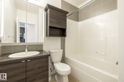 Contemporary bathroom featuring a dark wood-finish vanity with an integrated oval sink and dark countertop - 