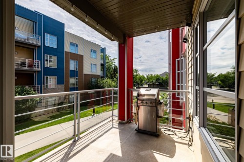 Covered patio featuring concrete flooring, a glass and metal railing, and an exterior wall with horizontal siding - #215 2590 Anderson Wy Sw, Edmonton, AB - Outdoor With Exterior
