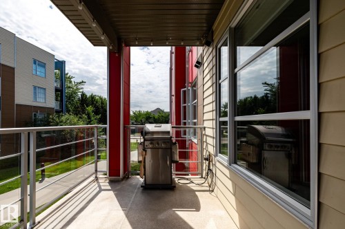 Private outdoor balcony with glass panel railing and composite decking - #215 2590 Anderson Wy Sw, Edmonton, AB - Outdoor With Exterior