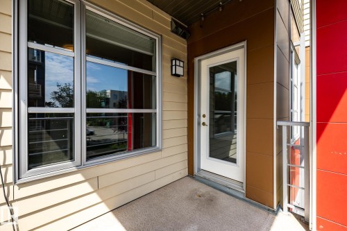 Private outdoor patio featuring a concrete surface, contemporary exterior lighting, and a full-light entry door - #215 2590 Anderson Wy Sw, Edmonton, AB - Outdoor With Deck Patio Veranda With Exterior