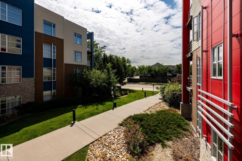 Modern multi-story building featuring vibrant red and blue paneling - #215 2590 Anderson Wy Sw, Edmonton, AB - Outdoor