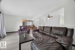 Open-concept living space featuring light wood-finish flooring, a ceiling fan with integrated lighting, and a wide entryway leading to an additional dining area - 
