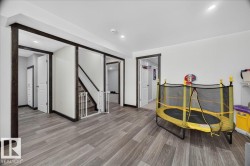 Spacious room featuring wood-finish flooring, recessed lighting, and dark wood trim - 