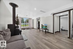 Spacious living area featuring wood-finish flooring, a contemporary black wood-burning stove, and recessed lighting - 