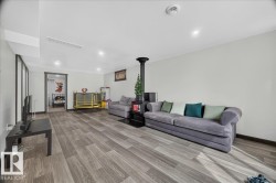 Spacious room featuring wood-finish flooring, recessed lighting, a modern freestanding fireplace, and neutral wall tones - 
