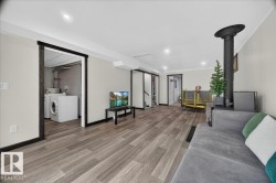 Spacious room featuring wood-finish flooring, recessed lighting, and a prominent dark wood stove - 