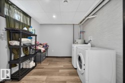 Dedicated laundry area featuring a front-loading washing machine, a top-loading dryer, and wood-finish flooring - 