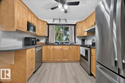 Kitchen featuring natural wood-finish cabinetry, stainless steel appliances, grey countertops, and a white subway tile backsplash - 