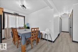 Dining area featuring light wood-finish flooring, white walls, and a contemporary black ceiling light fixture - 