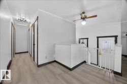 Hallway with light wood-finish flooring, white walls, and dark trim - 