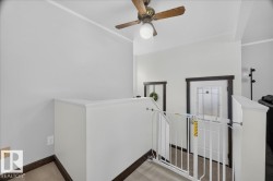 Upper-level landing featuring a ceiling fan with integrated lighting, light wood-finish flooring, and crisp white trim - 